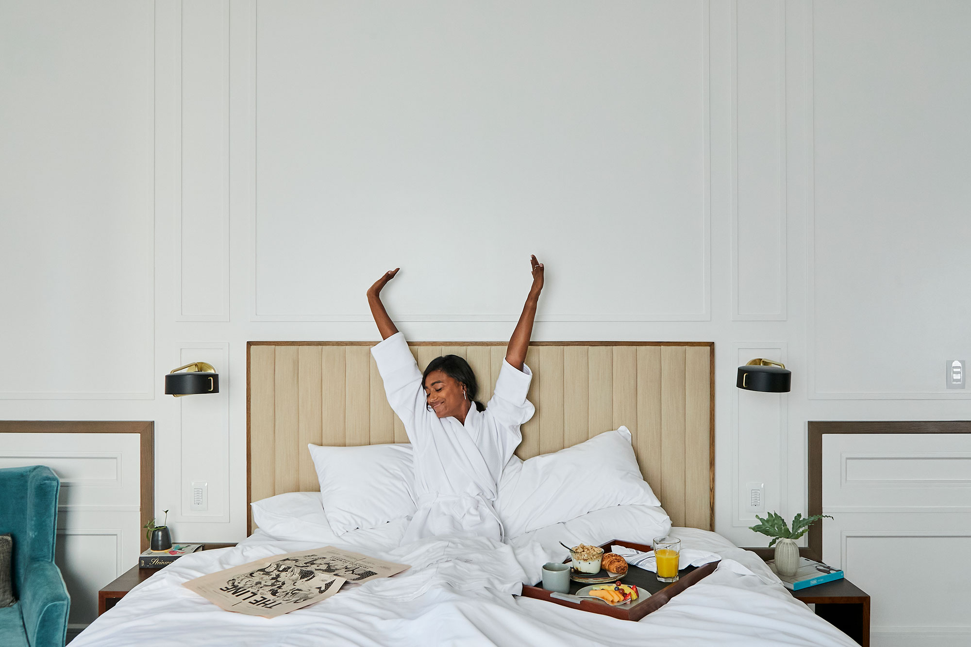 A woman stretching while having breakfast in bed