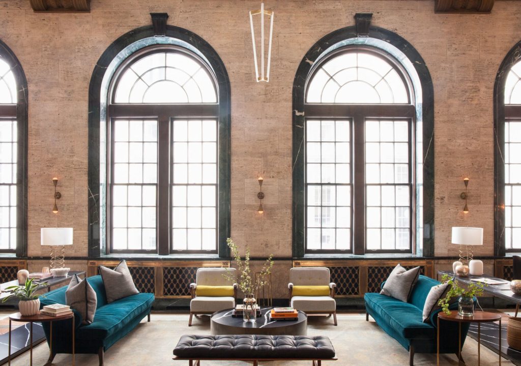 view of lobby area with teal couches and yellow accent pillows on white chairs